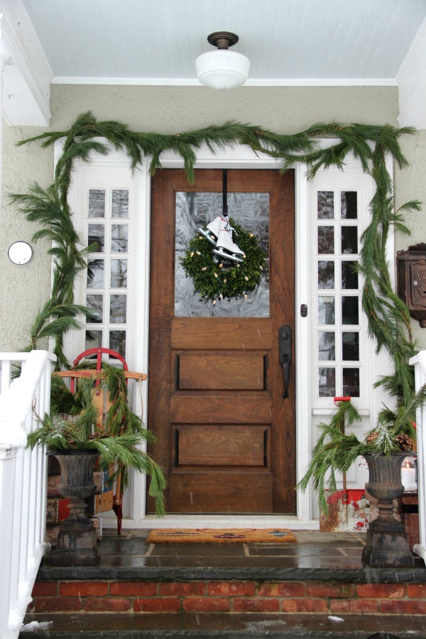 Beautiful Christmas porch - love the fresh garland around the door kellyelko.com