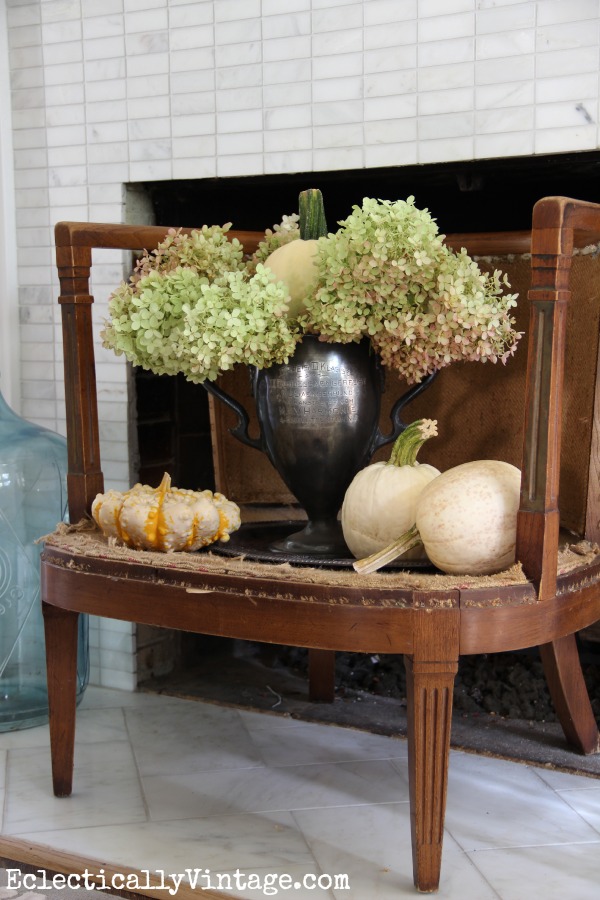 Turn an old chair into a fireplace screen - love the trophy filled with pumpkins and hydrangeas kellyelko.com