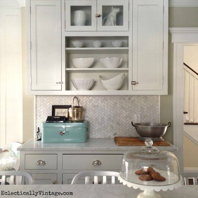 Love these open shelves filled with white kitchen accessories - and the herringbone carrara marble backsplash is gorgeous! kellyelko.com