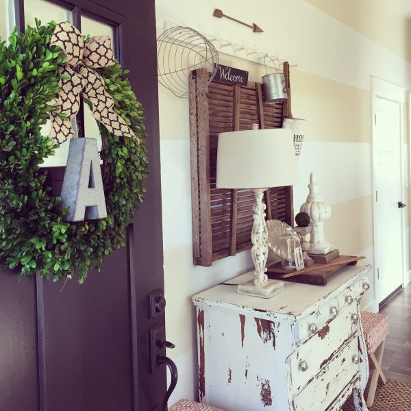 Love the dramatic black front door leading into this beautiful foyer with striped walls and the architectural element on the wall kellyelko.com