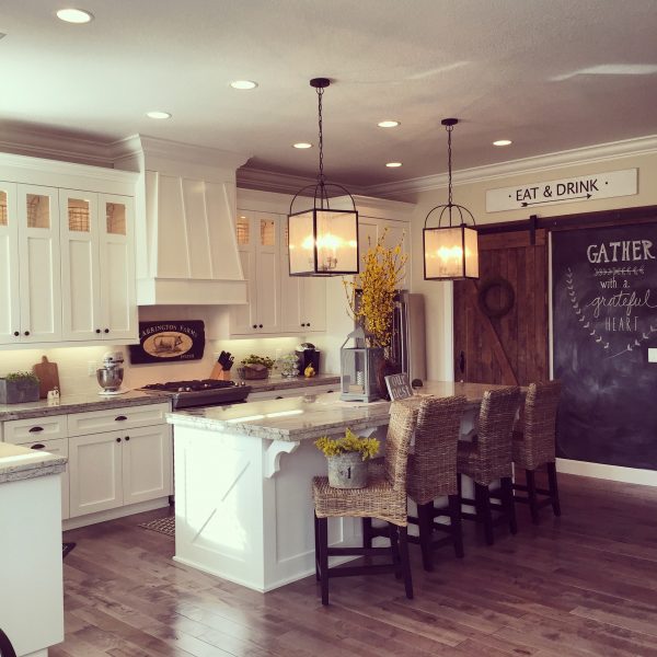 Love this white kitchen with lots of farmhouse flair including the rolling barn wood door, chalkboard wall and double lanterns over the large island kellyelko.com