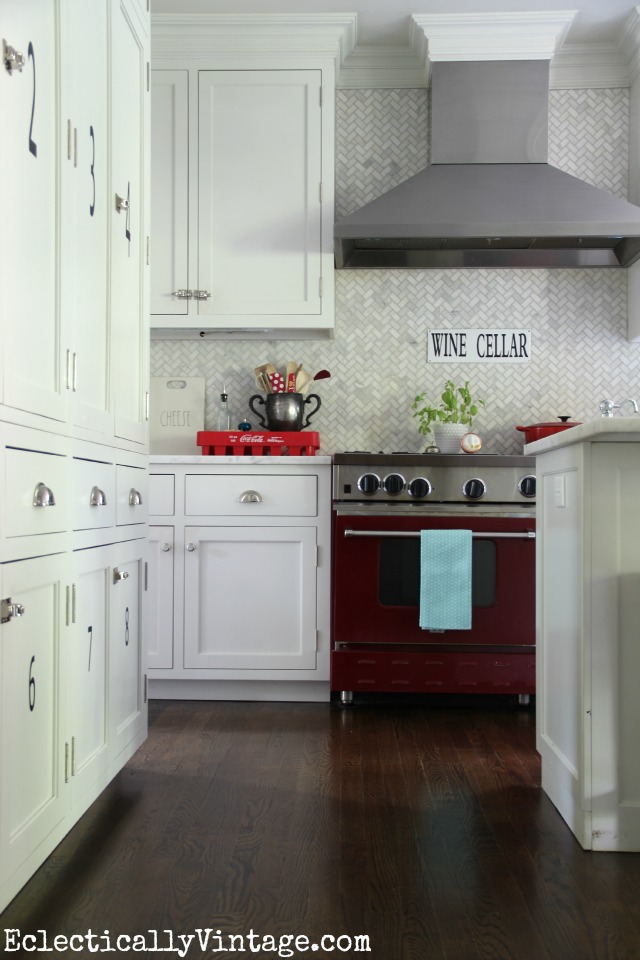 Love everything about this white kitchen - the marble herringbone tile, the red stove, the wine cellar sign ... kellyelko.com