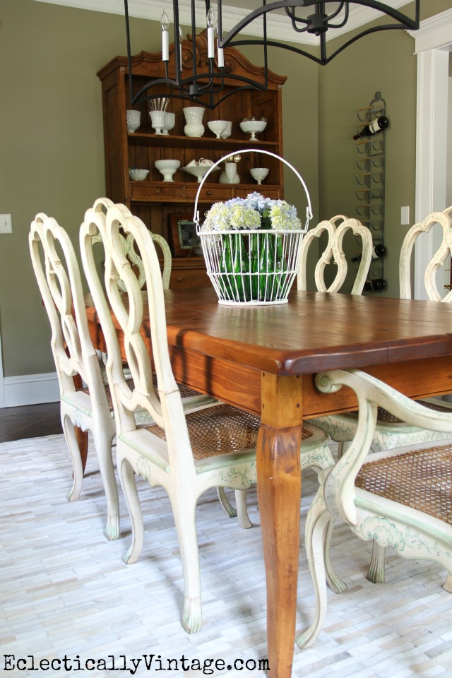 Love this rustic farmhouse table, french country chairs, cowhide rug, double chandeliers and more in this eclectic dining room kellyelko.com