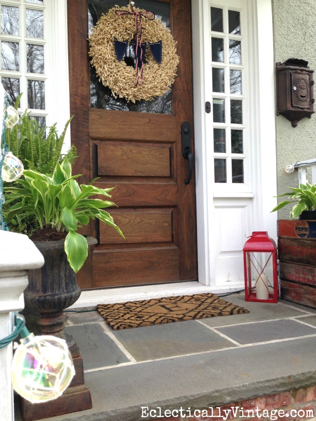 Summer porch decorating ideas - this porch screams summer with a welcoming wreath, plants galore and even fun buoy lights kellyelko.com 