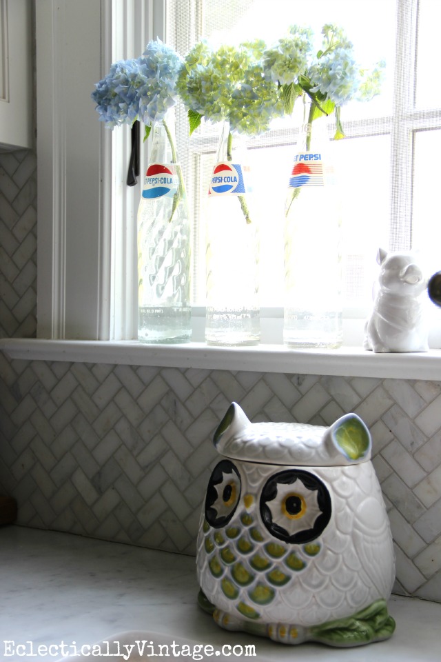 Love this kitchen window with the vintage Pepsi bottle vases and the owl cookie jar kellyelko.com