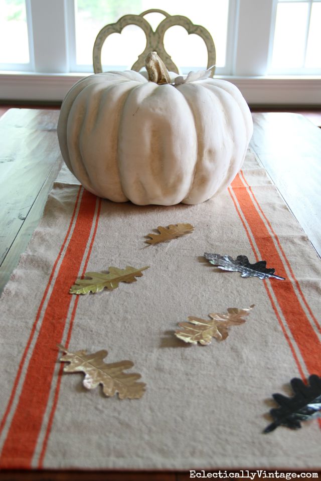 Love this fall centerpiece - a huge pumpkin, orange stripe table runner and DIY metal leaves kellyelko.com