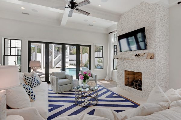 Coastal family room with fun touches like the rustic wood mantel and the shell and stucco fireplace surround - take the coastal home tour kellyelko.com