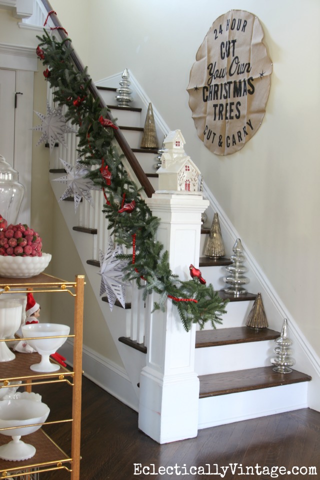 Love this bannister with garland, huge paper snowflakes and mercury glass trees on each stair kellyelko.com