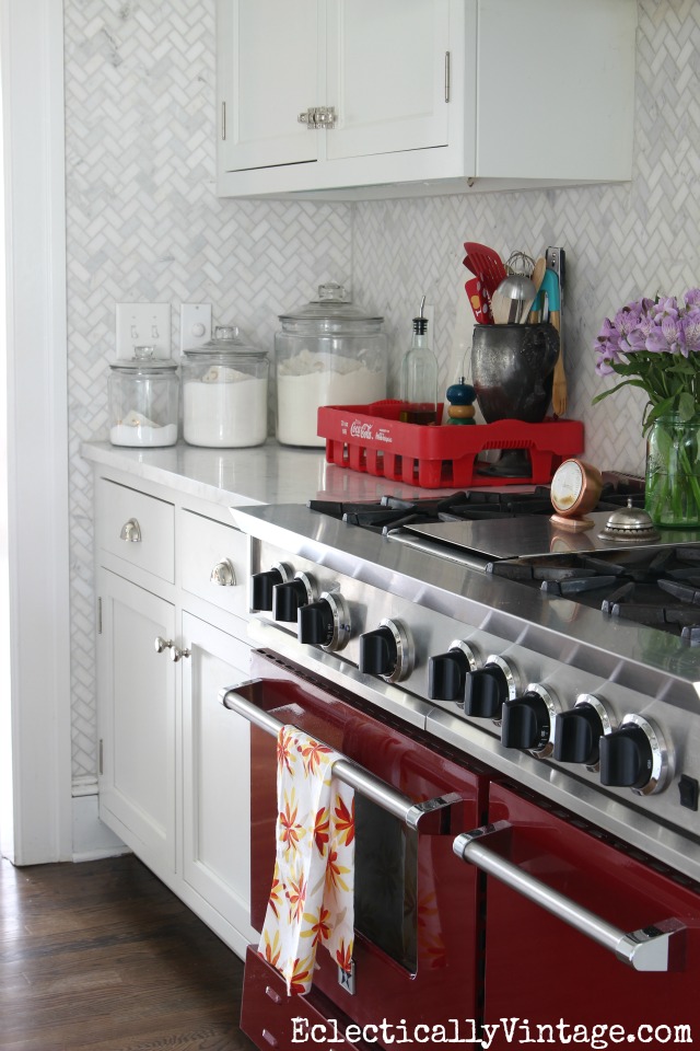 Wow! The red stove is such a fun idea in a white kitchen and love the floor to ceiling carrara marble herringbone backsplash kellyelko.com