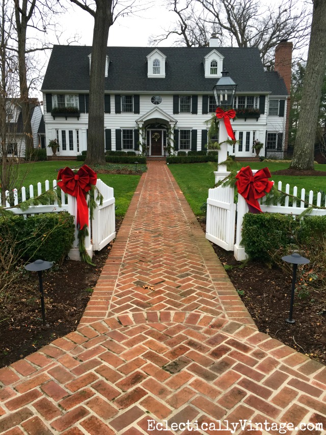 Classic Christmas Homes - love this white beauty decked out in greenery and festive red bows kellyelko.com