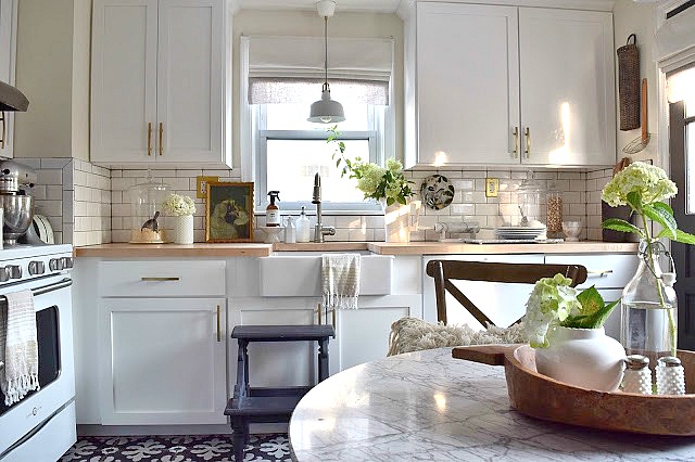 Love this small white kitchen with gold hardware and marble top table kellyelko.com