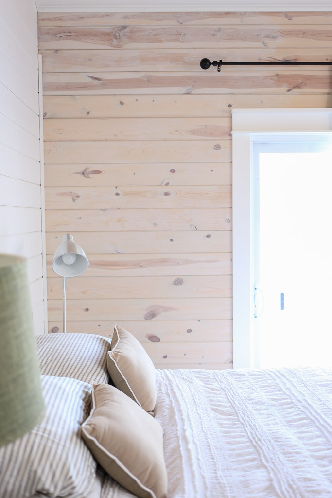 Horizontal knotty pine planked walls mix with painted planks in this cozy bedroom kellyelko.com