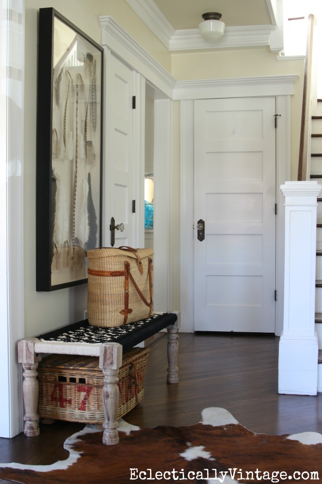 Beautiful foyer with woven bench, cowhide rug and feather art kellyelko.com