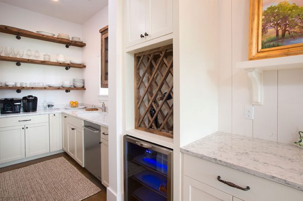 Rustic wood open shelves and wine storage add character to this white kitchen kellyelko.com