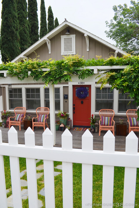 Love this cottage curb appeal with the vine covered pergola, picket fence and red front door kellyelko.com