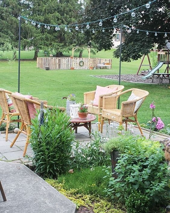 Farmhouse patio - love the cozy seating area with wicker chairs and string lights kellyelko.com