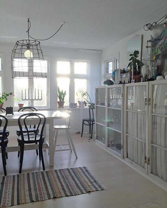 Love the built in glass cabinets in this white dining room with wire chandelier and black bentwood chairs kellyelko.com