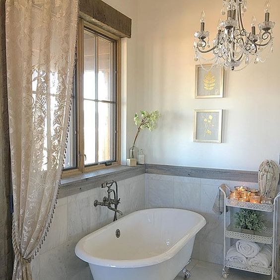 Love the claw foot tub and crystal chandelier in this farmhouse bathroom kellyelko.com