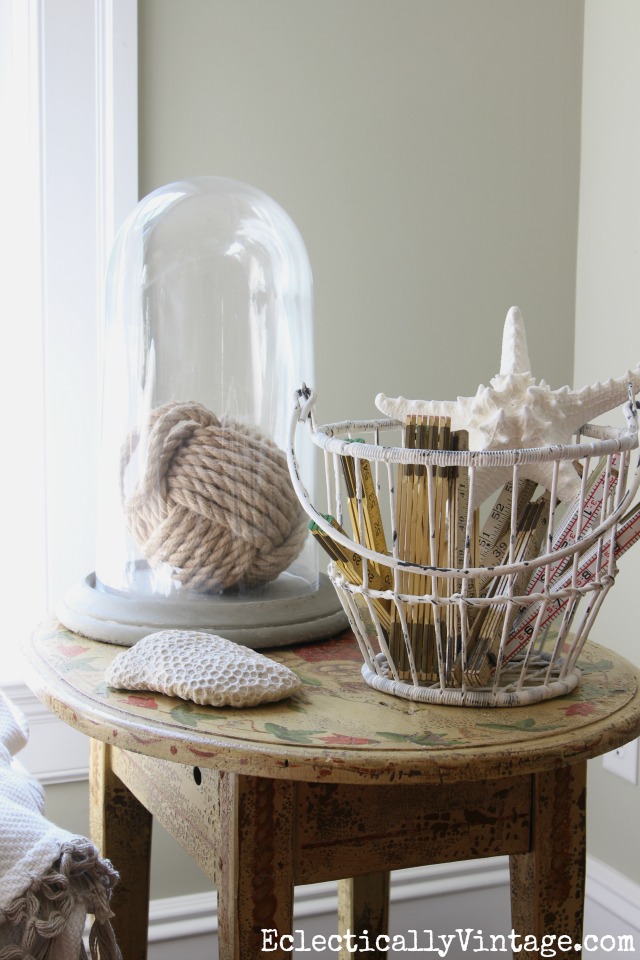 Love this coastal decor - the rope monkey ball under a cloche and a metal basket filled with old folding rulers and a starfish kellyelko.com